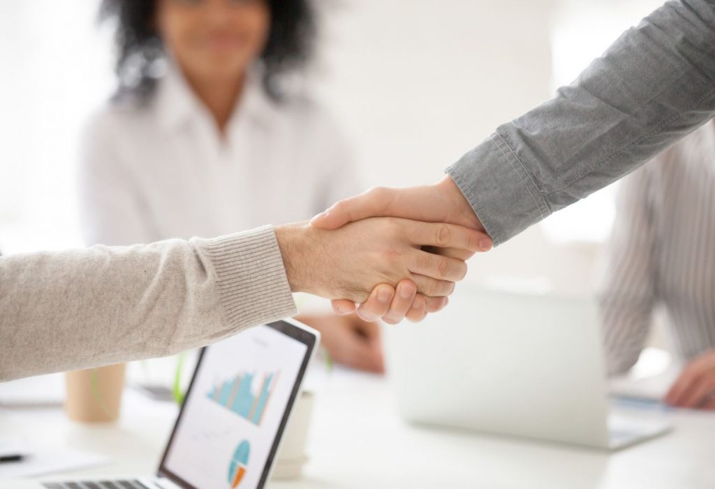 Foco em um aperto de mão entre duas pessoas fechando negócio