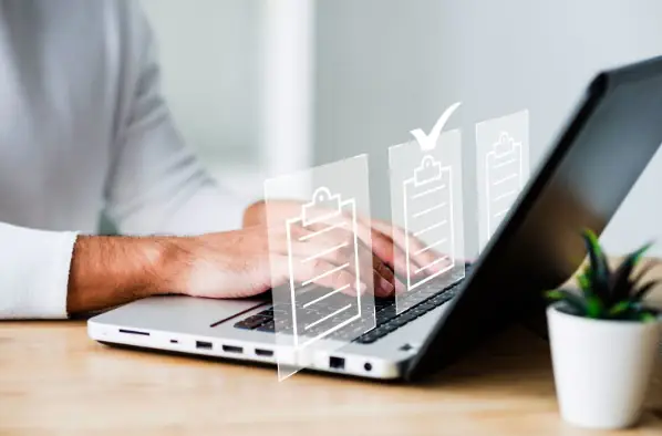Destaque para as mãos de um homem utilizando o notebook. Há três ícones projetados em frente à tela.
