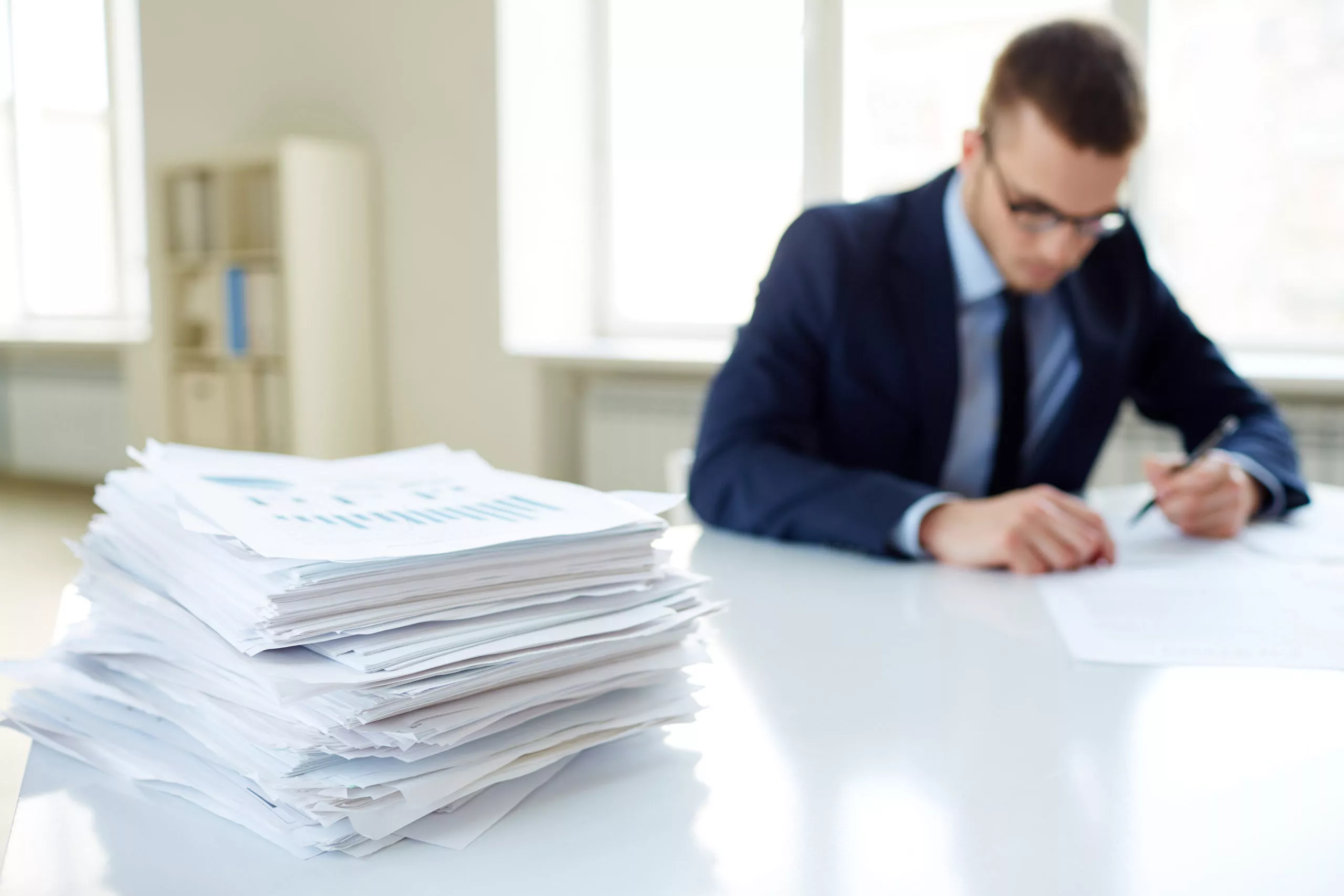 organização de documentos, homem com pilha de arquivos na mesa