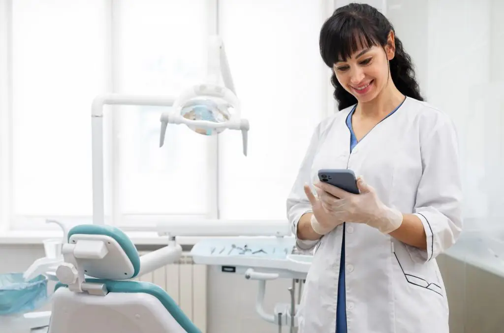 Dentista em consultório utilizando seu smartphone